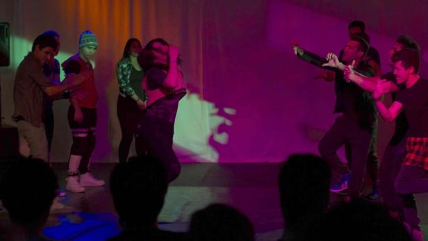 Eine Gruppe von Tänzern tritt auf einer Bühne vor Publikum auf.