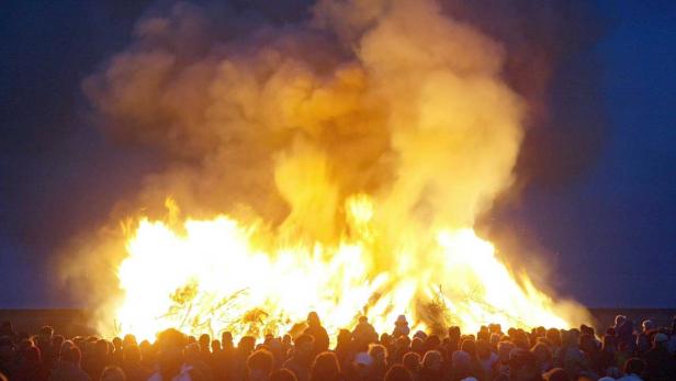 frühling Eine große Menschenmenge steht vor einem riesigen Lagerfeuer.