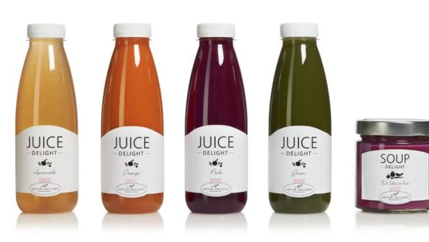 Fünf Flaschen und ein Glas mit Säften und Suppe der Marke „Juice Delight“.