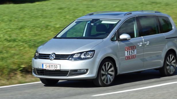 Ein silberner VW Sharan fährt auf einer Landstraße.