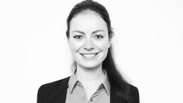 Porträt einer lächelnden Frau in Blazer und Bluse.