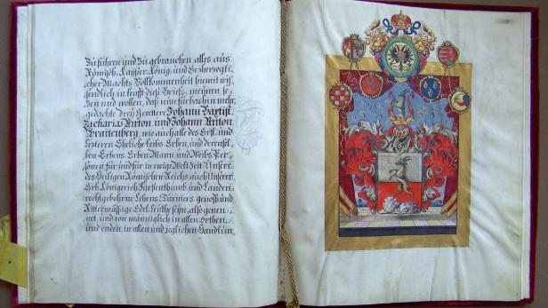 Eine geöffnete Buchseite mit einem Wappen und Text in alter Schrift.