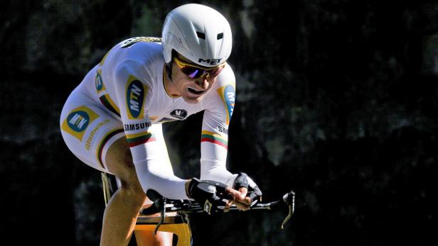Ein Radrennfahrer in weißem Trikot und Helm fährt ein Zeitrennen.