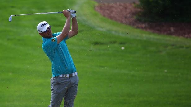 Ein Golfspieler schlägt einen Ball auf einem grünen Golfplatz.