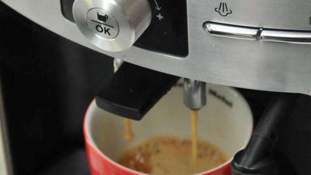 Eine Espressomaschine füllt eine rote Tasse mit Kaffee.