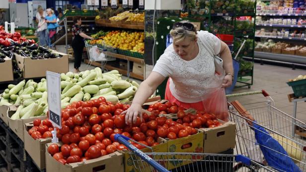 Eine Frau wählt Tomaten in einem Supermarkt aus.