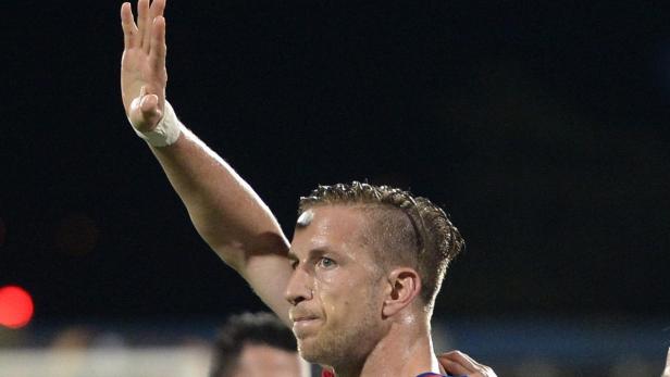 Ein Fußballspieler winkt mit erhobenem Arm.