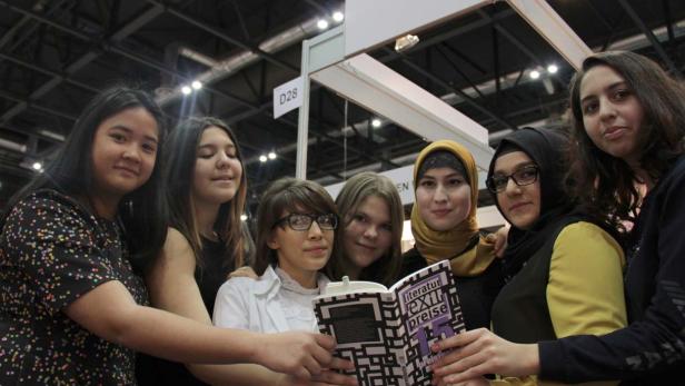 Eine Gruppe junger Frauen hält ein Buch mit dem Titel „Literaturpreise“ in den Händen.