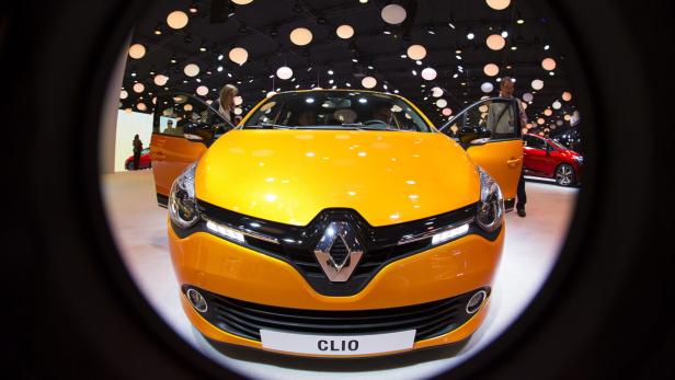 Ein orangefarbener Renault Clio auf einer Automobilausstellung mit geöffneten Türen.