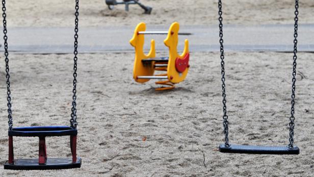 Ein Spielplatz mit zwei Schaukeln und einem gelben Wipptier.