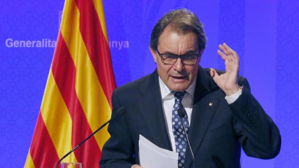 Ein Mann mit Brille gestikuliert vor der Flagge Kataloniens.