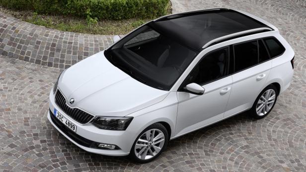 Ein weißer Škoda Fabia Combi mit schwarzem Panoramadach steht auf einem gepflasterten Platz.