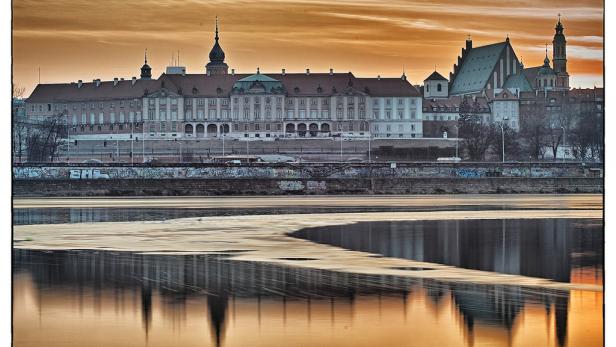 Das Königsschloss und die Altstadt von Warschau spiegeln sich im Wasser.