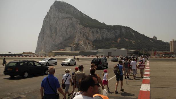 Pedestrians and drivers cross the tarmac of the Gibraltar Internacional airport in front of the Rock of the British Colony of Gibraltar, in Gibraltar, southern Spain August 4, 2013. Spain is studying retaliatory measures against the British territory of Gibraltar in an escalating dispute over fishing grounds, Spanish Foreign Minister Jose Manuel Garcia-Margallo said in an interview published on Sunday. REUTERS/Jon Nazca (GIBRALTAR - Tags: POLITICS TRANSPORT)