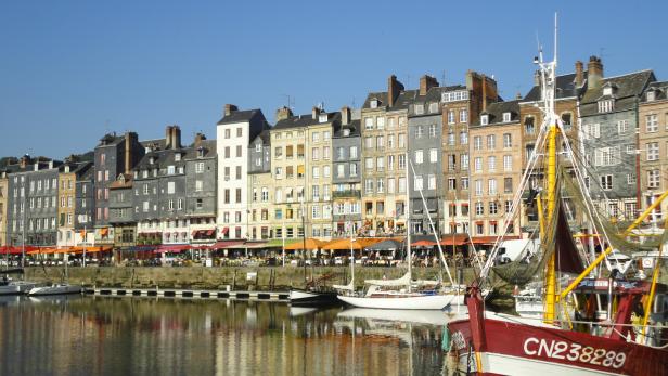 Blick auf den Hafen von Honfleur mit historischen Häusern und Fischerbooten.