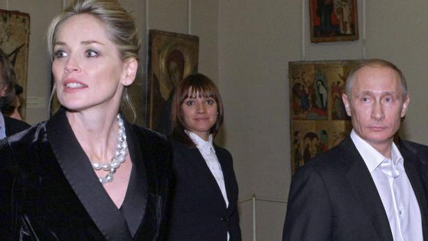 Sharon Stone und Wladimir Putin posieren vor Gemälden.