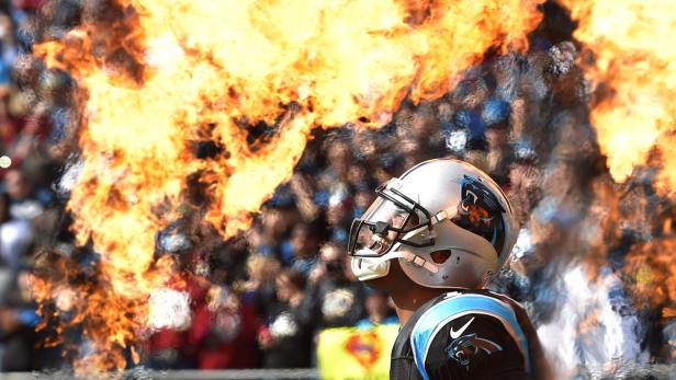 Ein Footballspieler der Carolina Panthers steht vor einer Feuerwand.