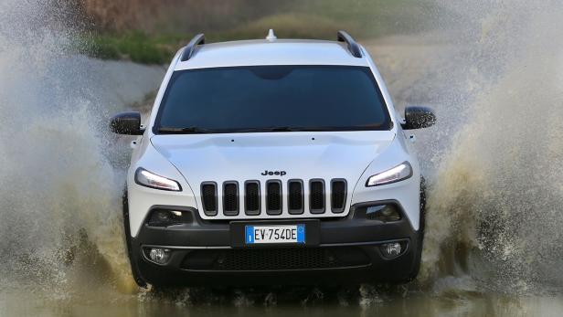 Ein weißer Jeep Cherokee fährt durch eine Wasserfläche.