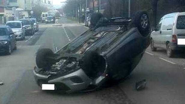 Ein Auto liegt auf einer Straße auf dem Dach.