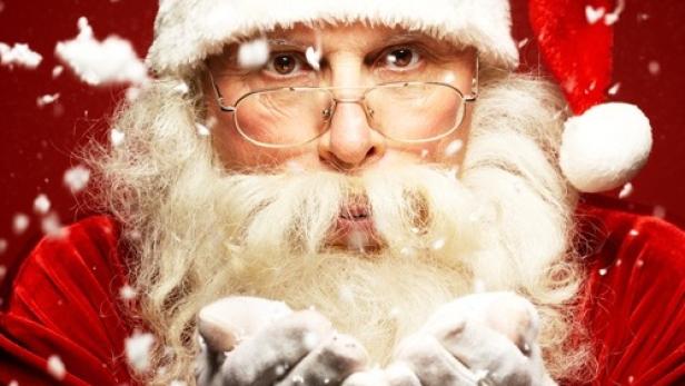 Der Weihnachtsmann pustet Schnee in seine Hände.