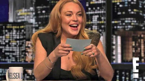 Unbenannt-55.jpg Lindsay Lohan liest lachend von einem Zettel vor einem Hintergrund mit einer Skyline.