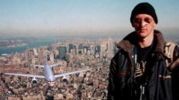 Ein Mann steht vor der Skyline von New York, während ein Flugzeug auf die Stadt zufliegt.