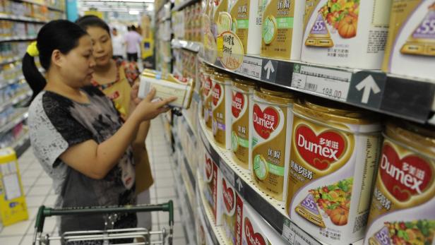 Zwei Frauen betrachten Babymilchpulver der Marke Dumex in einem Supermarktregal.