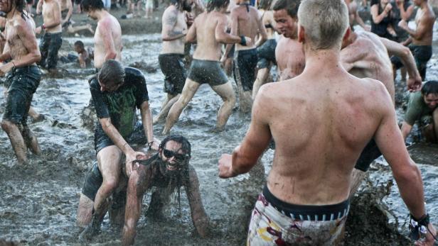 Eine Gruppe von Menschen watet und spielt in schlammigem Wasser.