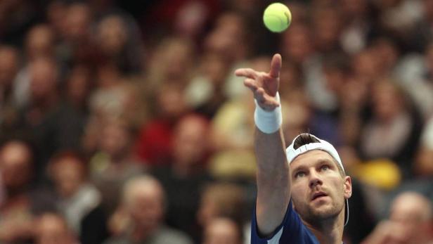 Ein Tennisspieler wirft einen Ball zum Aufschlag hoch.