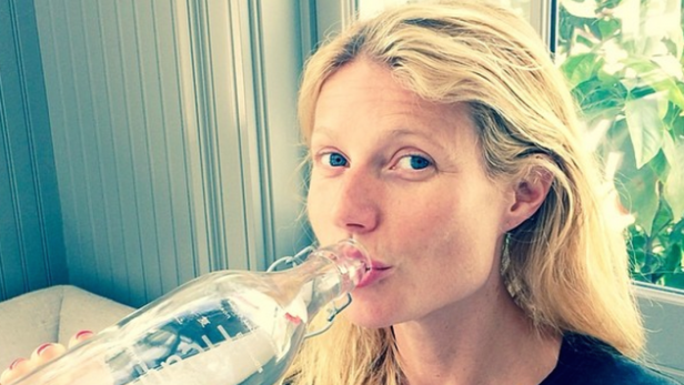Gwyneth Paltrow trinkt aus einer Glasflasche.