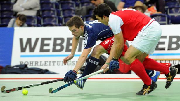 Zwei Hockeyspieler kämpfen um den Ball auf dem Spielfeld.