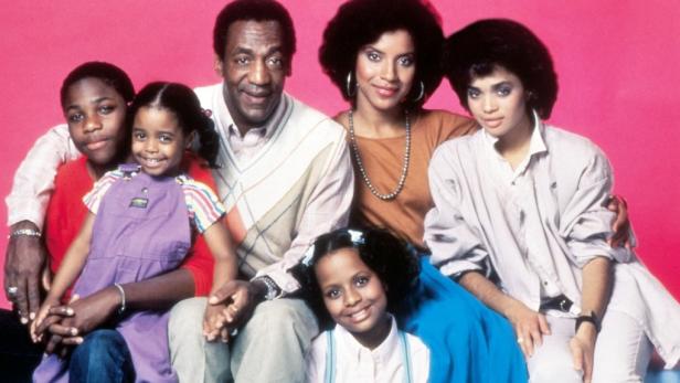 Die Familie Huxtable, darunter Bill Cosby und Phylicia Rashad, posiert vor einem pinkfarbenen Hintergrund.