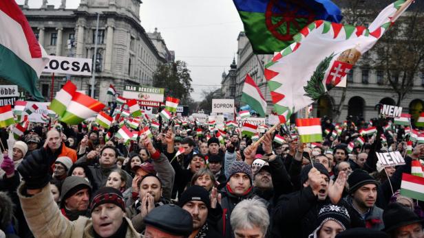 epa03494362 Protesters shout slogans and wave Hungarian national flags, and a Roma flag (2-R), during a demonstration near the Parliament building in Budapest, Hungary, 02 December 2012. Upset has been caused by comments made by one of the Jobbik legislators, Marton Gyongyosi, who said that Jews working in the government or parliament should be &quot;listed&quot; for &quot;posing a national security risk to Hungary.&quot; It took a full day for the government to issue a statement emphatically rejecting the comment from the Jobbik member, who has in the past cast doubt on the scope of the Holocaust. EPA/LASZLO BELICZAY HUNGARY OUT