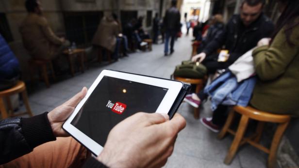 Eine Person schaut YouTube auf einem Tablet in einem belebten Café.