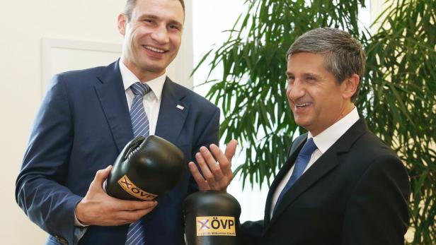 Vitali Klitschko und Michael Spindelegger halten Boxhandschuhe der ÖVP in die Kamera.