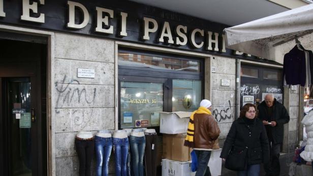 A street vendor displays jeans on the wall of a Monte Dei Paschi bank in Rome, December 10, 2012. The sudden acceleration in the political crisis over the weekend was enough to put Italy back into the spotlight of the euro zone crisis alongside Spain, whose yields also climbed on Monday on the back of the turmoil in Rome. REUTERS/Max Rossi (ITALY - Tags: POLITICS ELECTIONS BUSINESS SOCIETY)