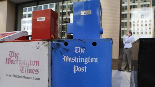 Washington Post (R) and Washington Times newspaper boxes are pictured outside the entrance to the Washington Post headquarters in Washington, August 5, 2013. Amazon Inc founder Jeff Bezos has agreed to buy the newspaper assets of the Washington Post Co , including its flagship daily, for $250 million. REUTERS/Stelios Varias (UNITED STATES - Tags: MEDIA BUSINESS)