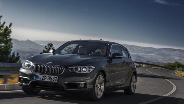 Ein grauer BMW fährt auf einer kurvenreichen Straße in den Bergen.