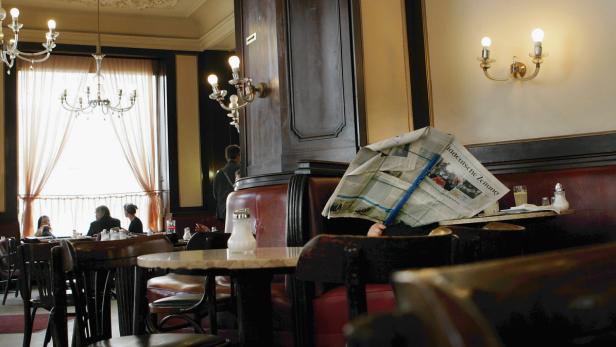 In einem Wiener Café liest eine Person hinter einer „Süddeutschen Zeitung“.