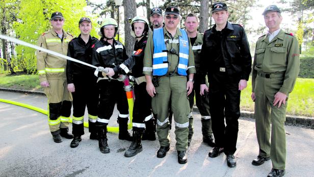 Eine Gruppe Feuerwehrleute posiert mit einem Wasserstrahl für ein Foto.