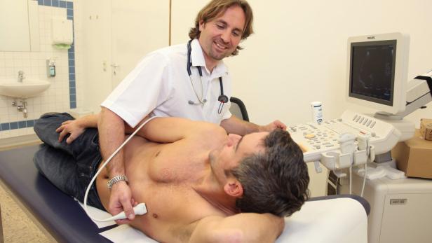 Ein Arzt führt eine Ultraschalluntersuchung bei einem Patienten durch.