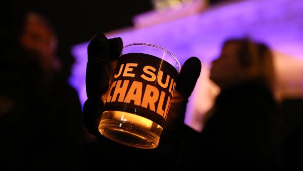 Eine Person hält eine Kerze mit der Aufschrift „Je Suis Charlie“.
