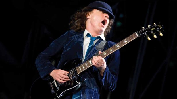 Angus Young von AC/DC spielt Gitarre auf der Bühne.