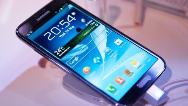 Ein Samsung-Smartphone zeigt den Startbildschirm mit Uhrzeit, Datum und verschiedenen Apps.
