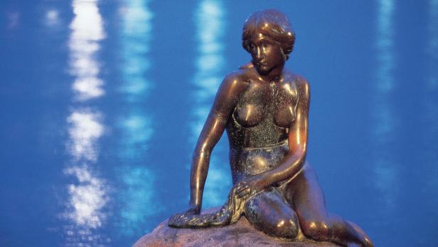 Die Bronzestatue der Kleinen Meerjungfrau in Kopenhagen sitzt auf einem Felsen.
