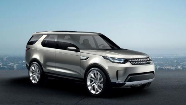 Ein silberner Land Rover Discovery vor einer Stadtkulisse.