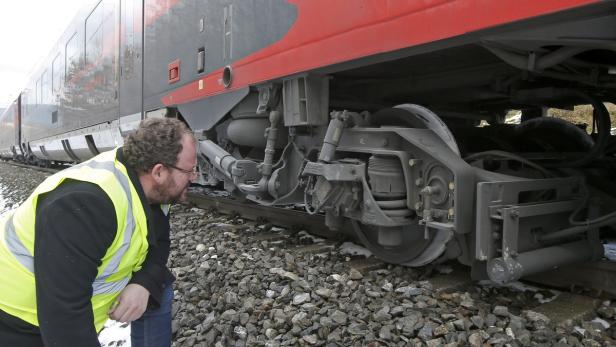 Ein Mann in Warnweste inspiziert das Fahrwerk eines Zuges.
