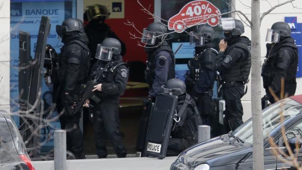Eine Gruppe von Polizisten in voller Montur steht vor einer Bank.