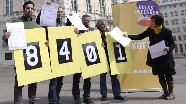 Menschen halten Schilder mit der Aufschrift „8401“ und Formulare für ein Volksbegehren hoch.