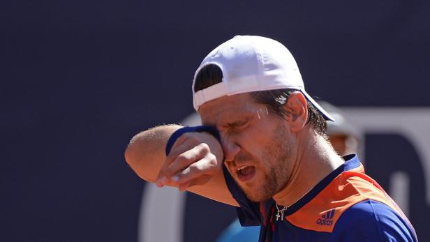 Ein Tennisspieler wischt sich den Schweiß von der Stirn.